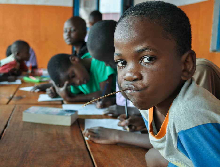 pupils writing at desks in a classroom Teso Elites Development Association - Teso Elites Development Association