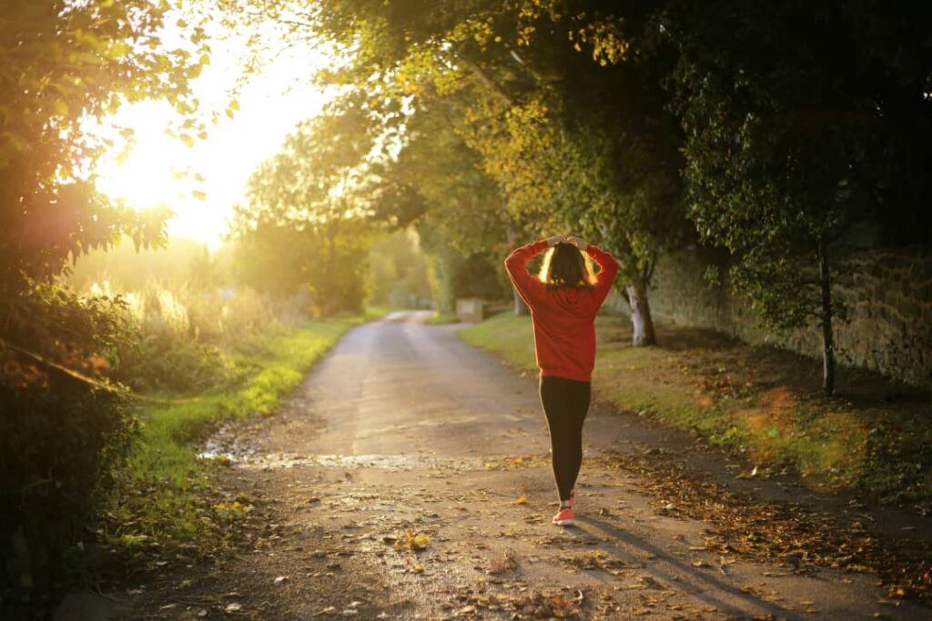 woman walking on a tree lined road at sunrise Teso Elites Development Association - Teso Elites Development Association