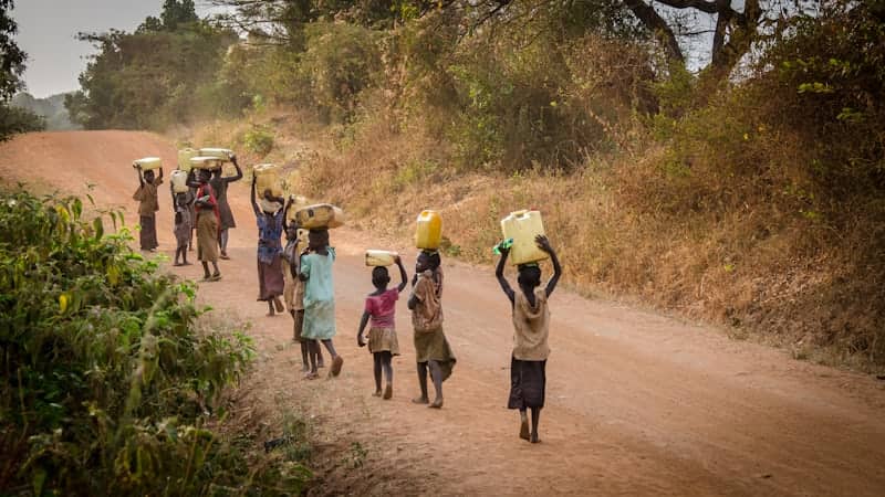 women and children carrying water on a village road Teso Elites Development Association - Teso Elites Development Association